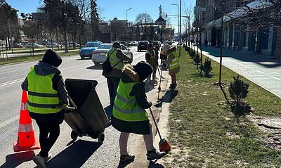 Angajați ai Primăriei Alba Iulia curățând străzile și trotuarele de praf și nisip acumulat.
