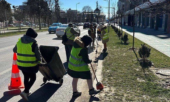 Angajați ai Primăriei Alba Iulia curățând străzile și trotuarele de praf și nisip acumulat.