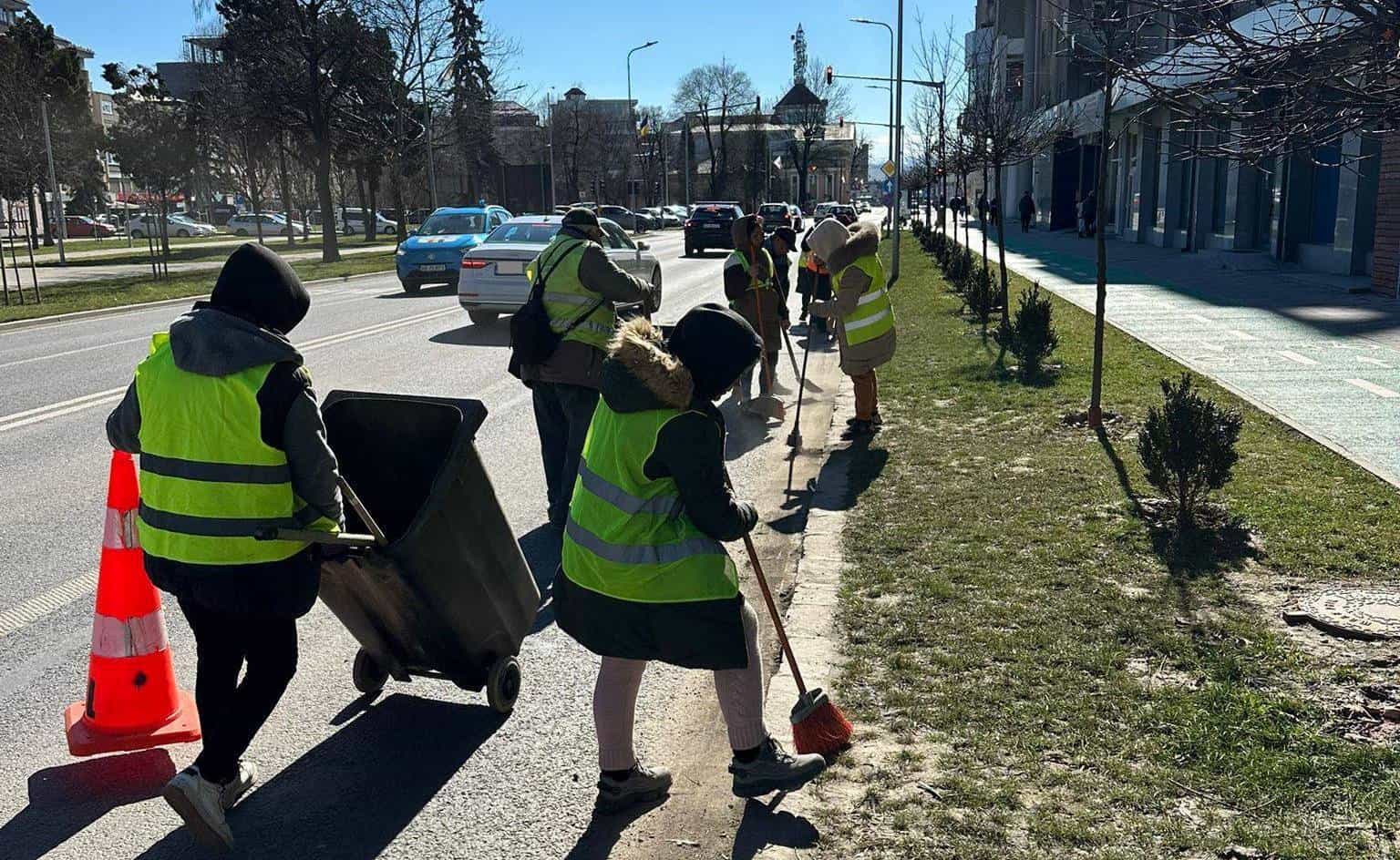Angajați ai Primăriei Alba Iulia curățând străzile și trotuarele de praf și nisip acumulat.