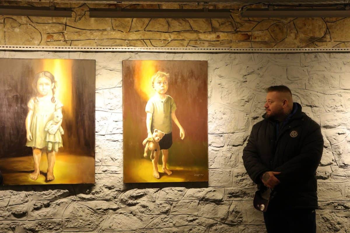 Bărbat admirând picturi cu copii în galeria penitenciarului Aiud.