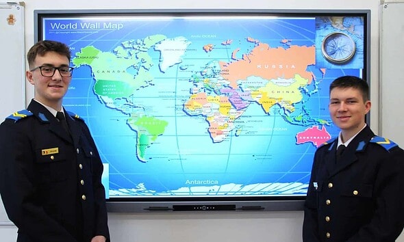 Elevi în uniformă militară în fața unui glob pământesc digital.