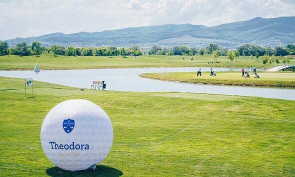 Teren de golf Theodora Golf Club în primăvară, cu jucători și peisaje verzi.