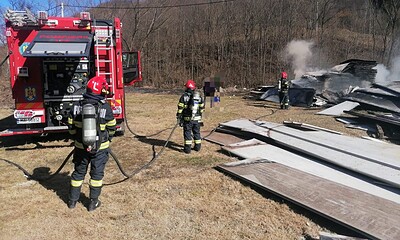 Echipaj de pompieri stingând focul la o construcție afectată de incendiu.