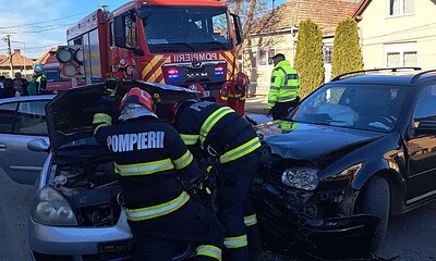 Impact între două autoturisme, pompieri intervenind la fața locului.