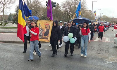 Participanți la marșul pentru viață, elevi și tineri, purtând drapele și icoane, în centrul orașului.