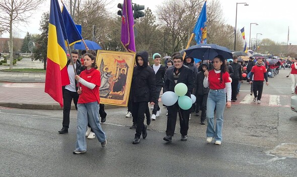 Participanți la marșul pentru viață, elevi și tineri, purtând drapele și icoane, în centrul orașului.