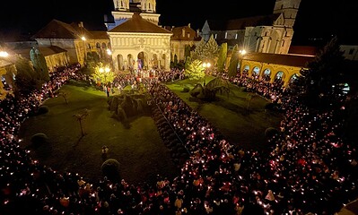 Procesiune de Paște cu lumina sfântă în curtea unei biserici din România.