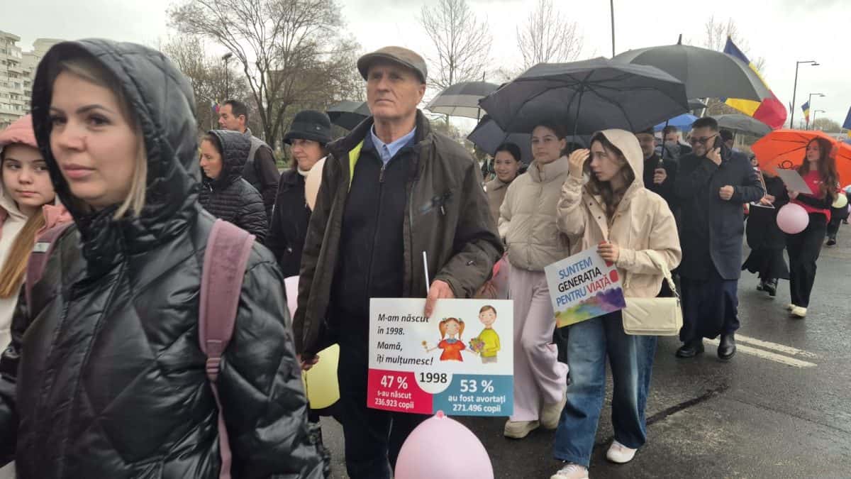 Participanți la marșul anti-avort din Alba Iulia, cu umbrele și pancarte, susținând dreptul la viață.