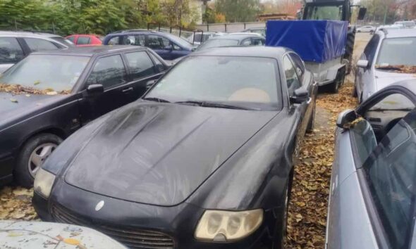 Mașină Audi neagră, pregătită pentru licitație, expusă în parcare cu alte vehicule.