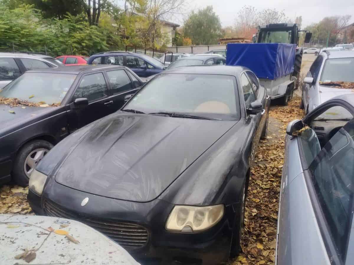 Mașină Audi neagră, pregătită pentru licitație, expusă în parcare cu alte vehicule.