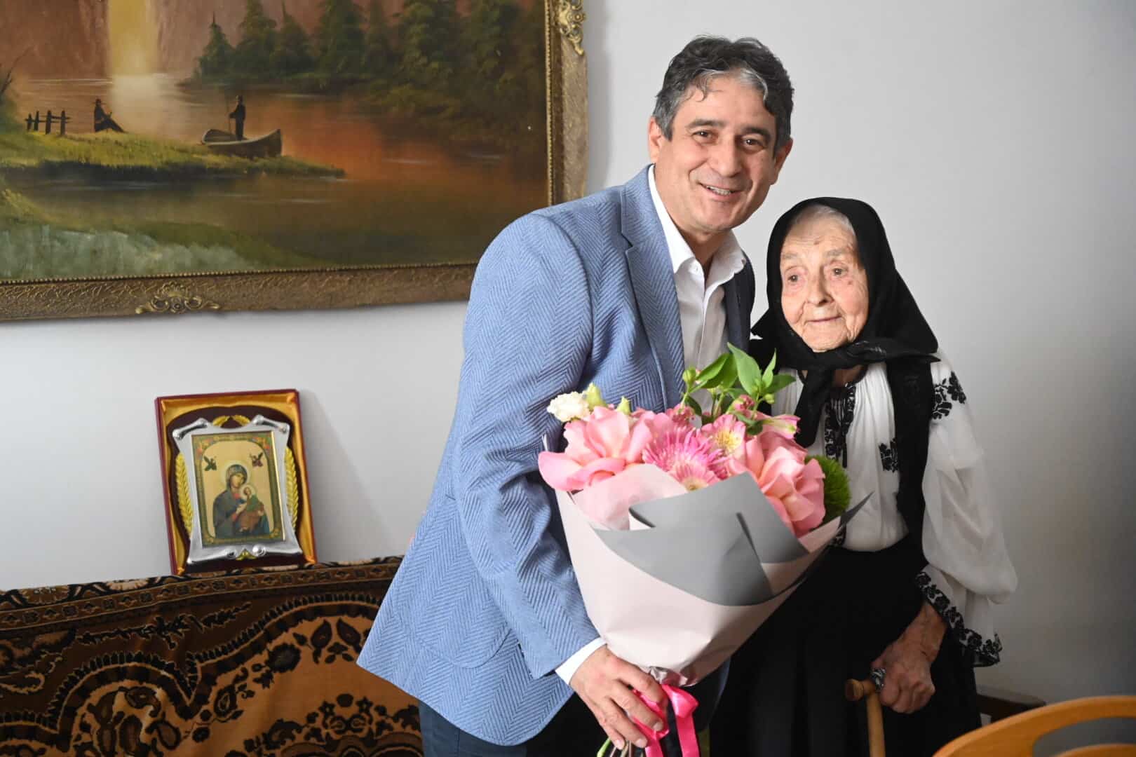 Primarul îi oferă flori unei femei de 106 ani din Alba Iulia, într-un moment special de aniversare.