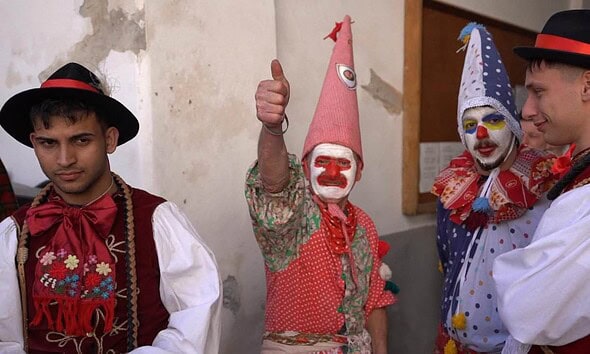 Grup de oameni în costume tradiționale și măști de carnaval la ritualul Fărșang din Rimetea.