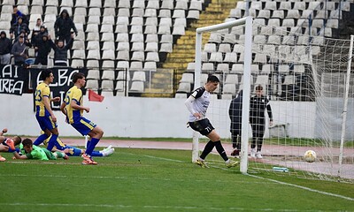 Jucători în luptă pentru gol, cu un goalkeeper pregătit să apere poarta.