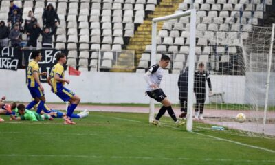 Jucători în luptă pentru gol, cu un goalkeeper pregătit să apere poarta.