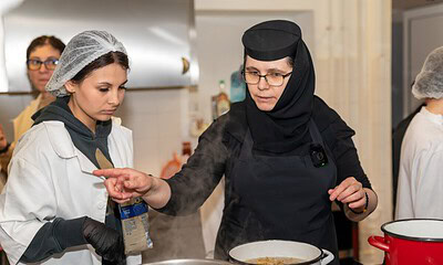 Două maici învățând elevii Colegiului Economic să prepare mâncare la mănăstire.