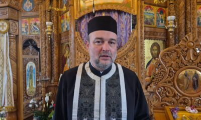 Imagine cu preot ortodox în interiorul bisericii, înconjurat de icoane și decoruri religioase elabor.